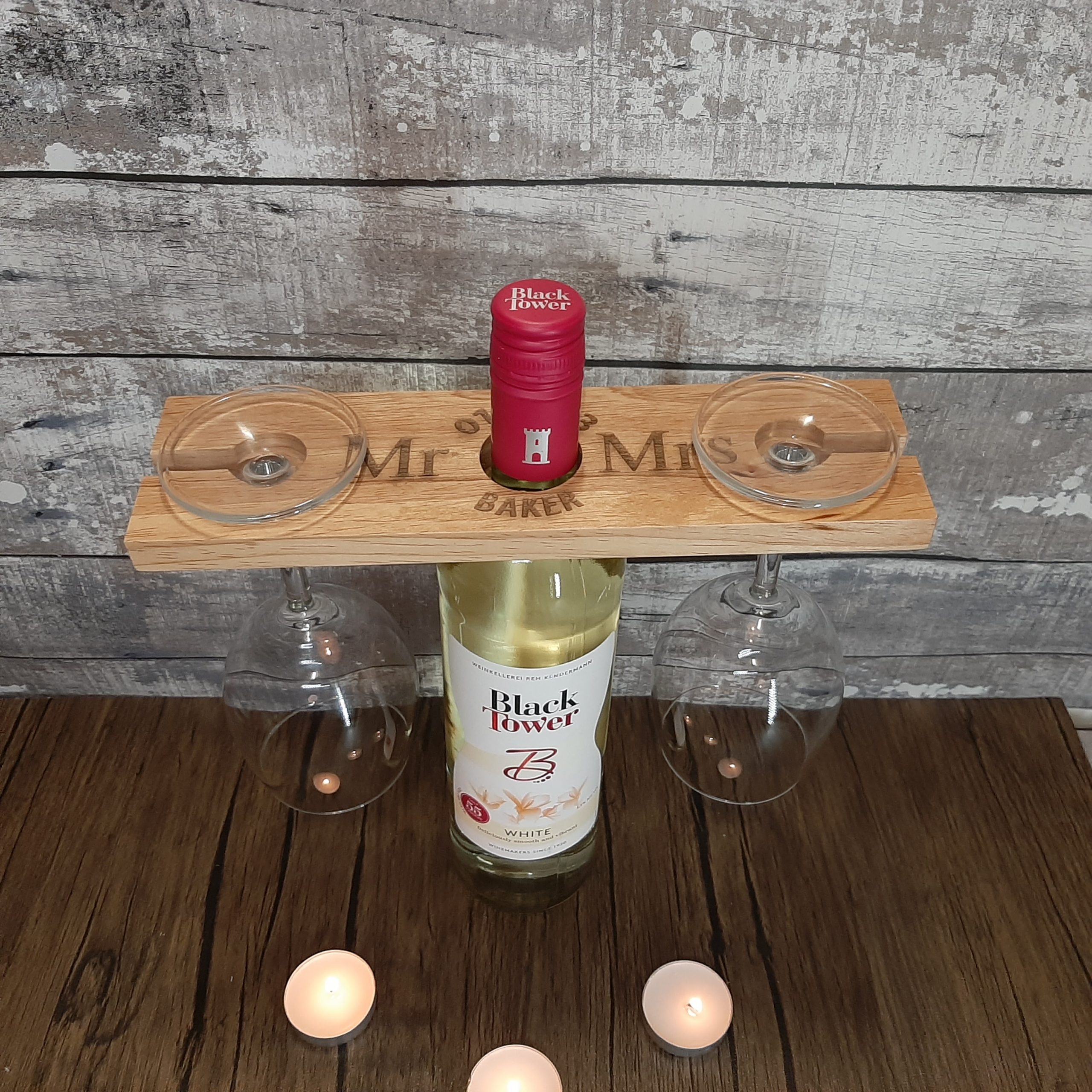 Laser Engraved Wine Glass Holder with hanging glasses on a bottle of wine at an angle to see the personalised Mr & Mrs wedding anniversary details