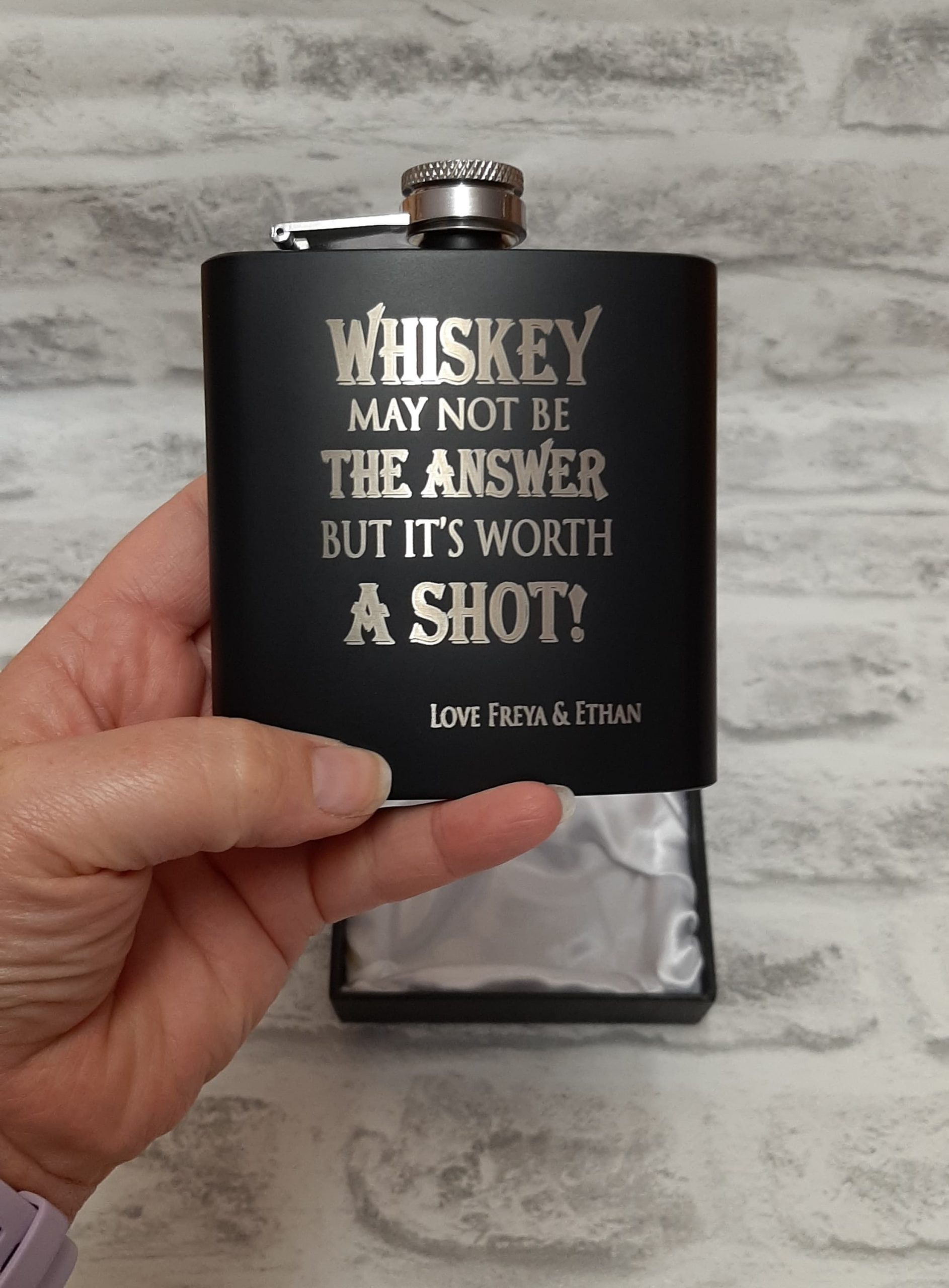 Black hip flask gift set in hand with custom whiskey shot quote engraved