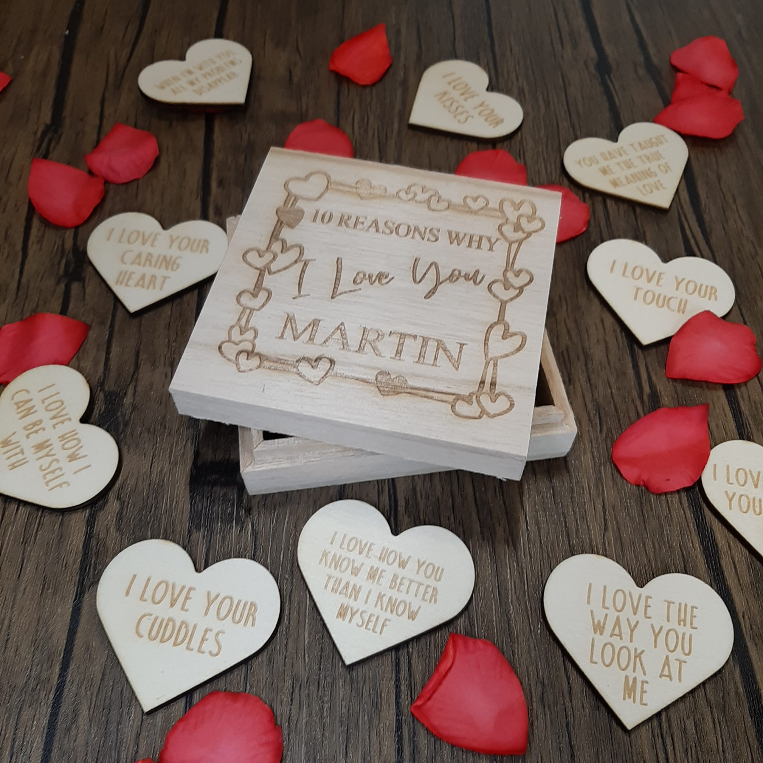 10 Reasons Why I Love You Token Box zoomed in to show wooden heart tokens with personalised messages with rose petals displayed for valentines day