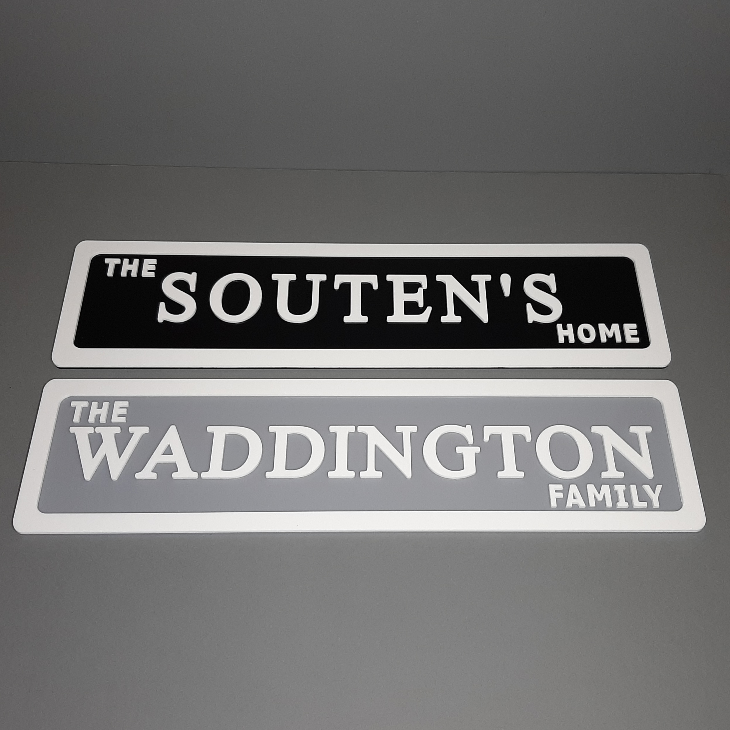 black and white sign above a grey and white family name sign