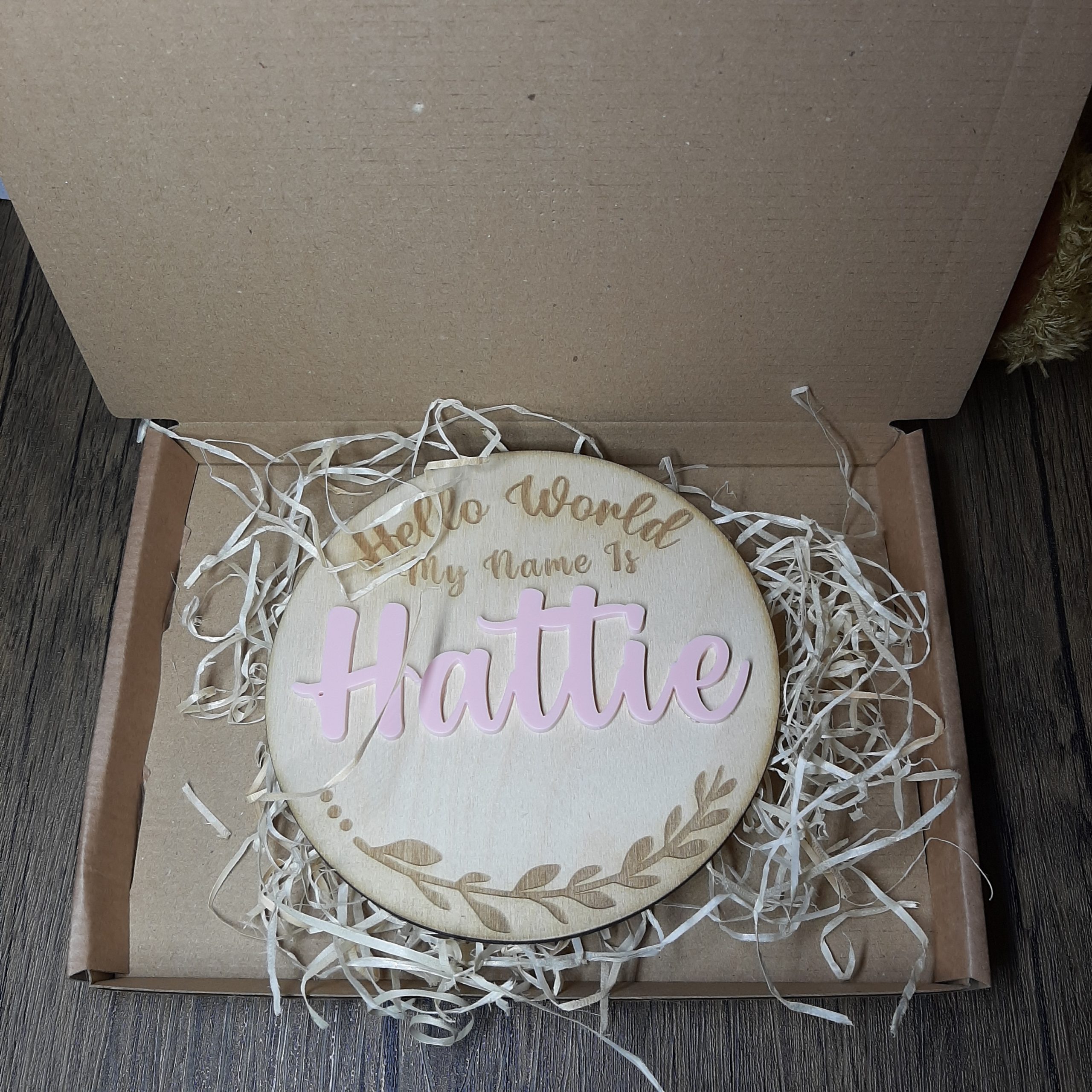 welcome baby sign in box, showing the engraved hello world, with acrylic pink name