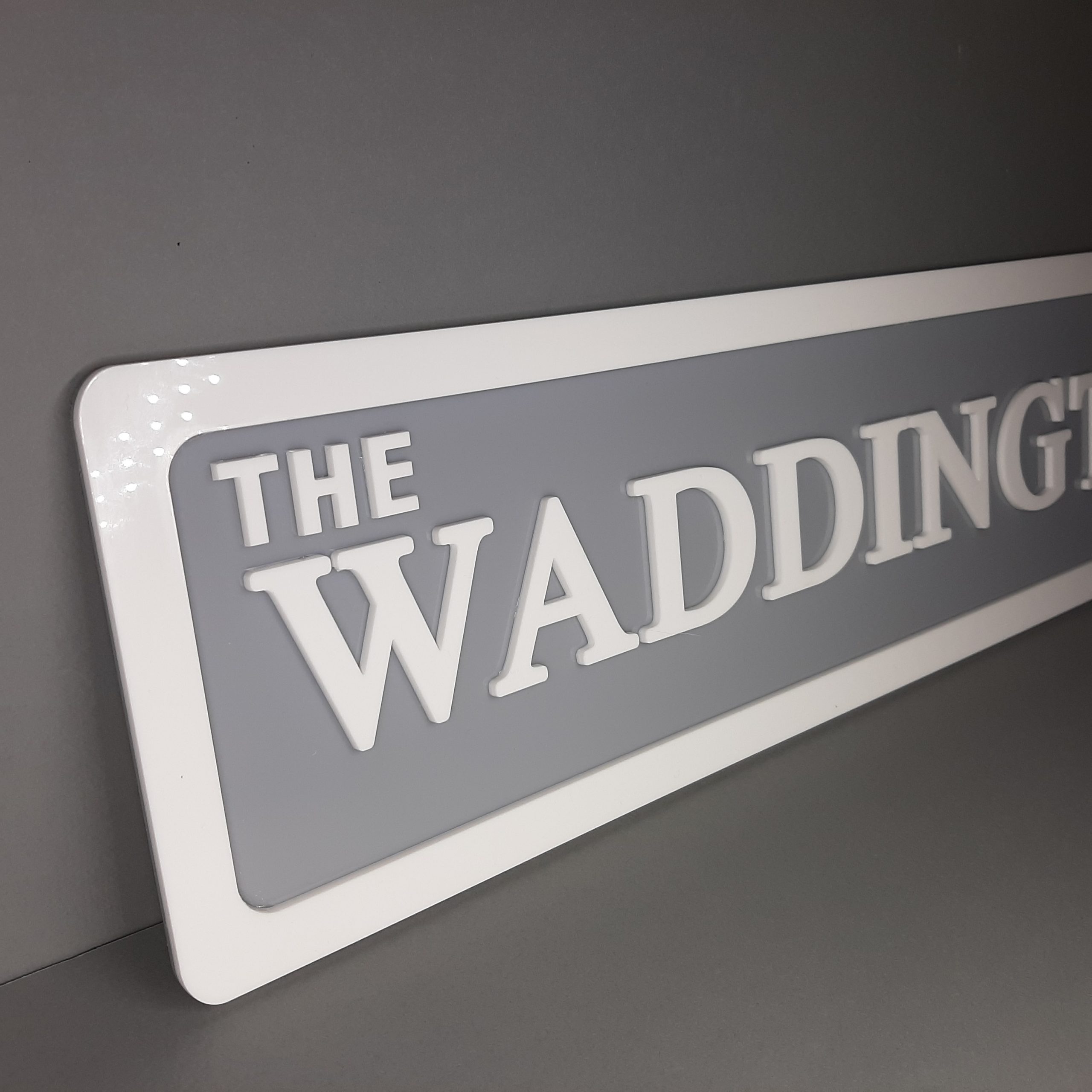 corner of the grey and white family name sign showing acrylic depth 3d look