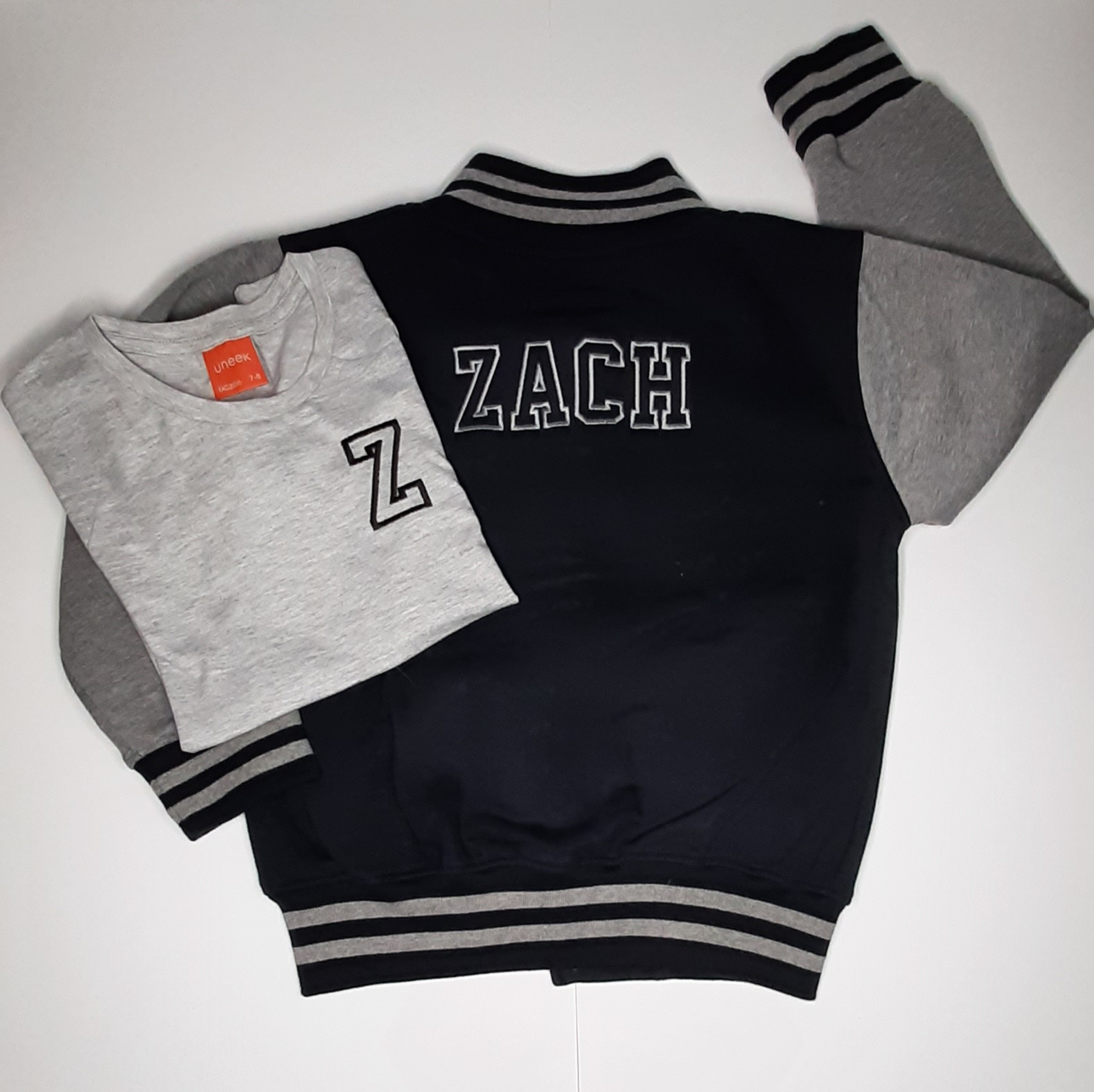 Children's varsity jacket on model in black and grey with embroidered name with matching t shirt