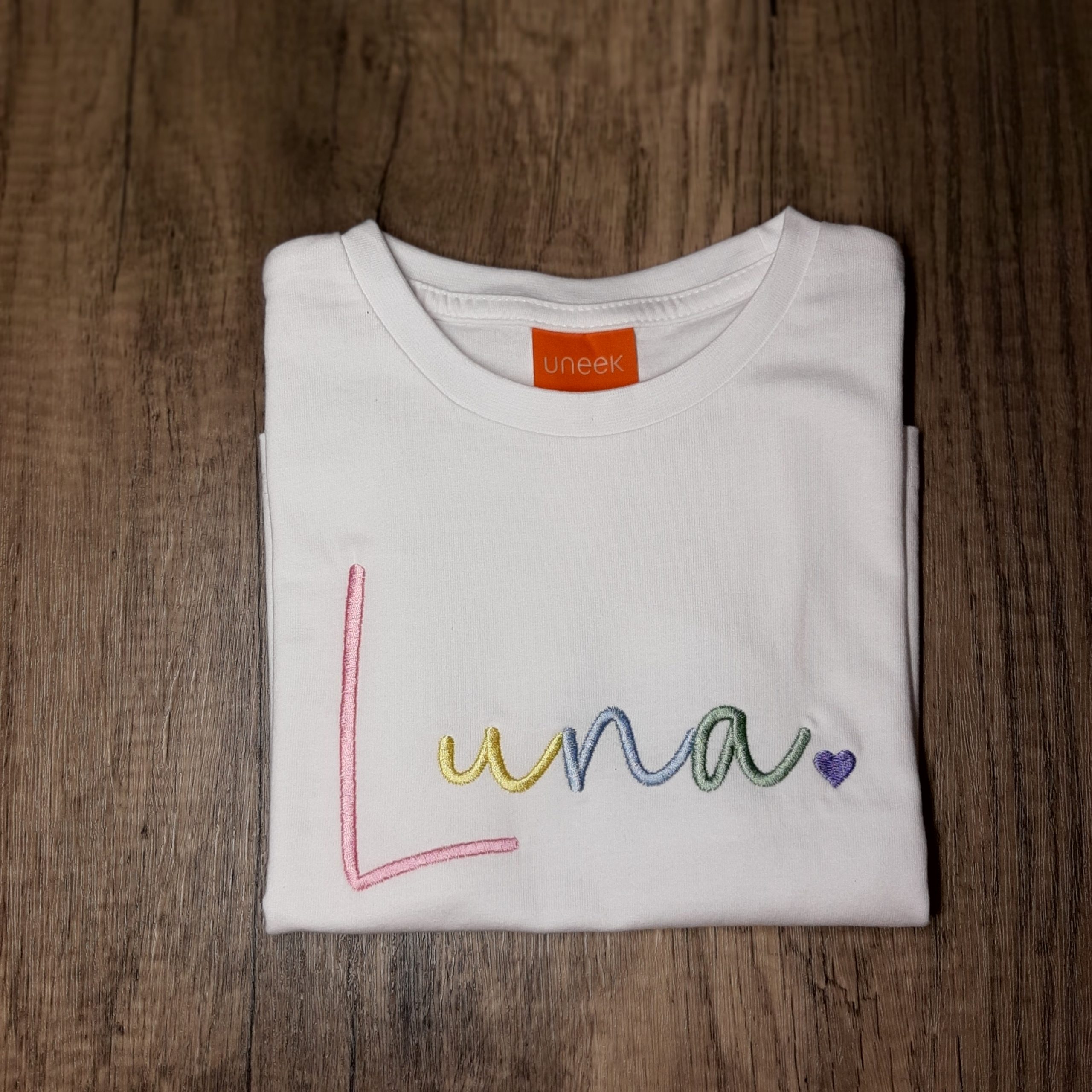 Rainbow Name Children's T Shirt/Jumper in rainbow pastel embroidered name, folded on the floor