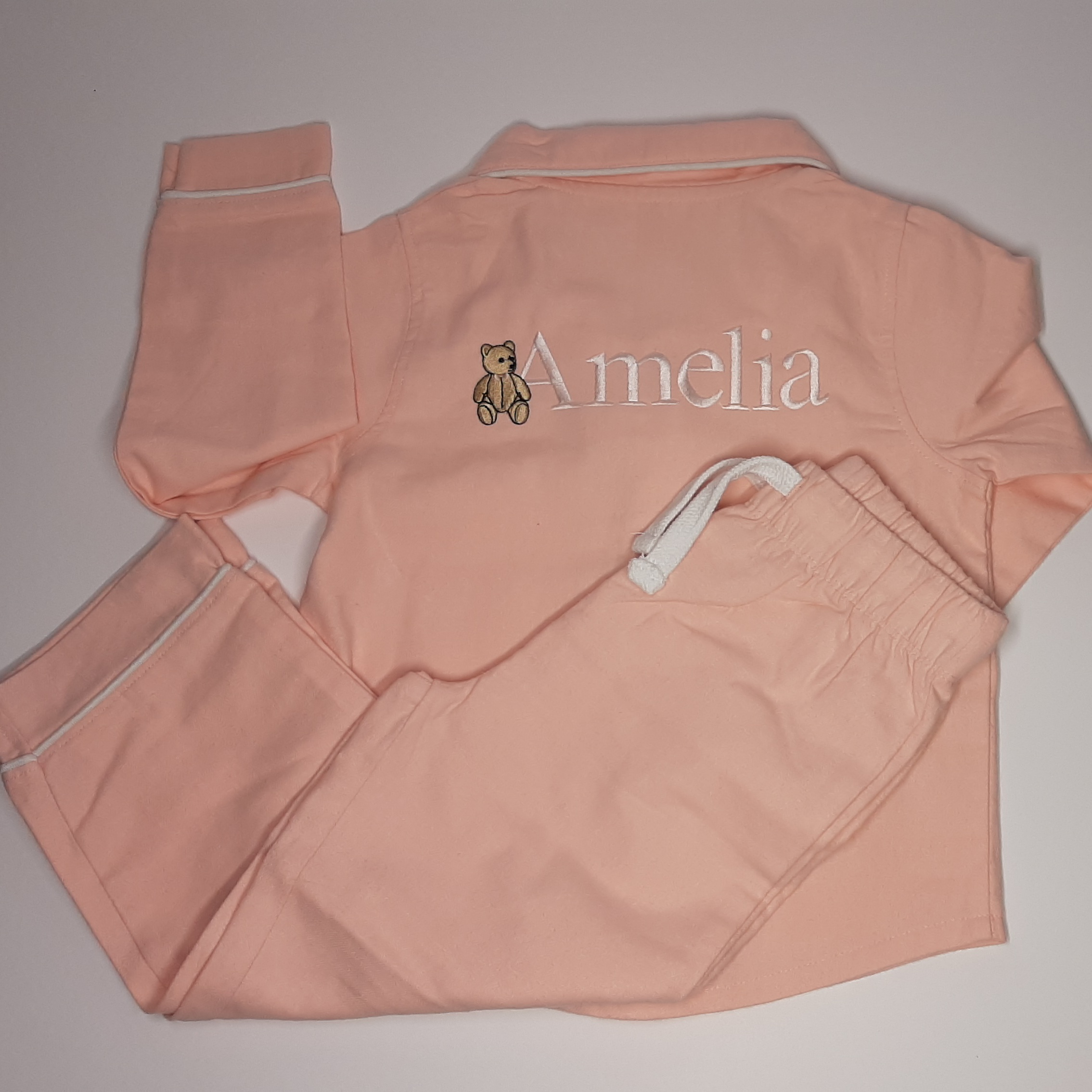 dusky pink classic children's pj on the back, with embroidered name with bear