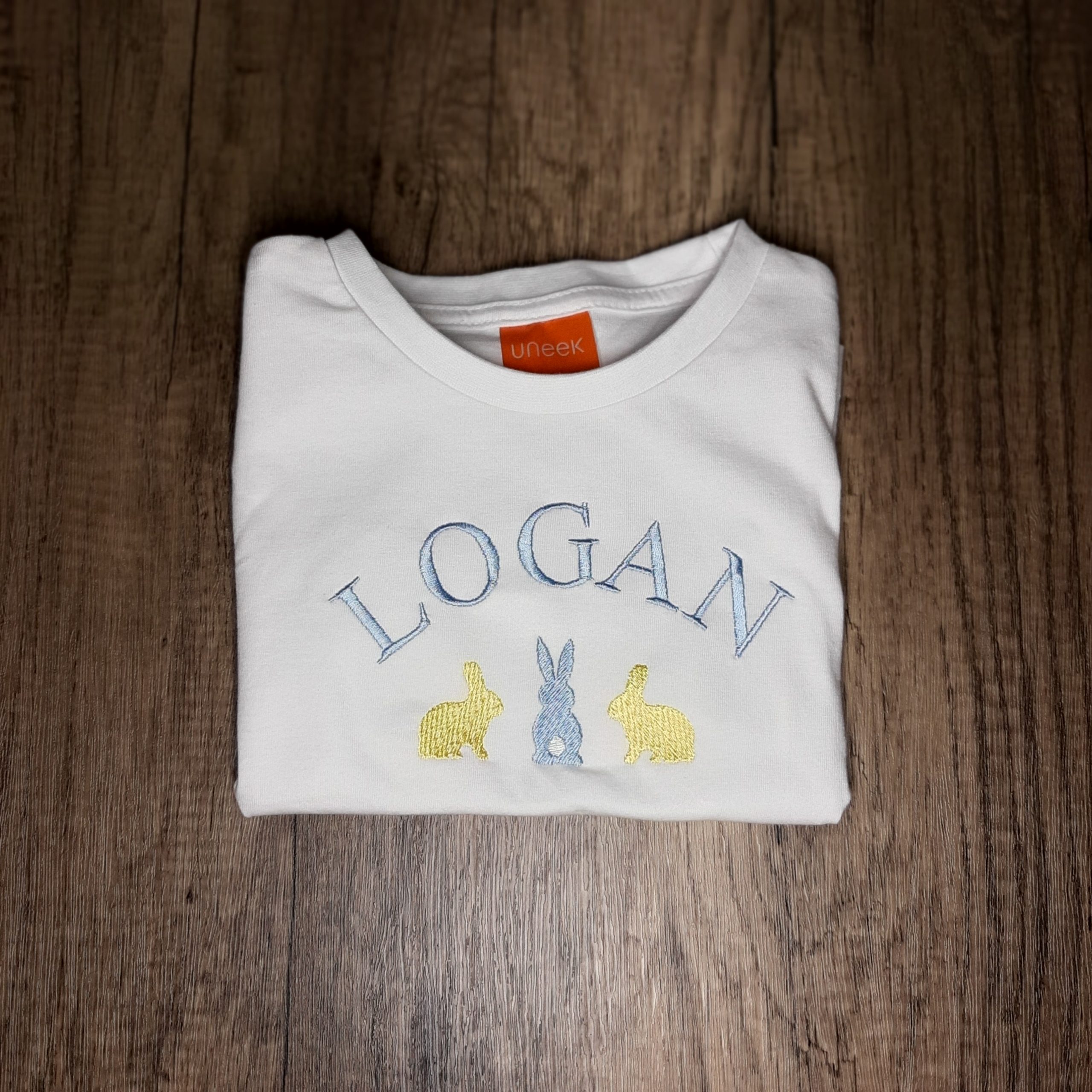 Folded white children's t shirt with 3 bunny embroidered design in pastel colours with name, rabbit design for easter