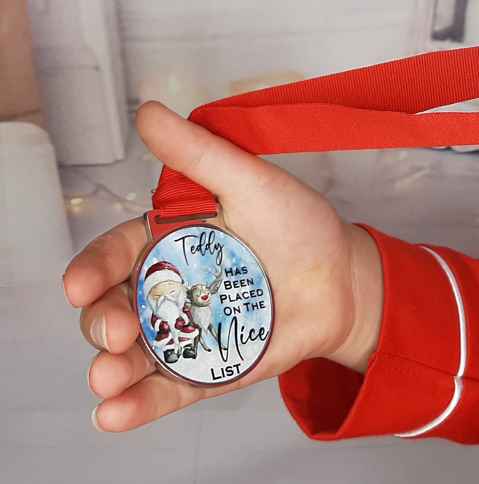 close up of made the nice list medal with red ribbon with santa reindeer personalised with name close up in hand