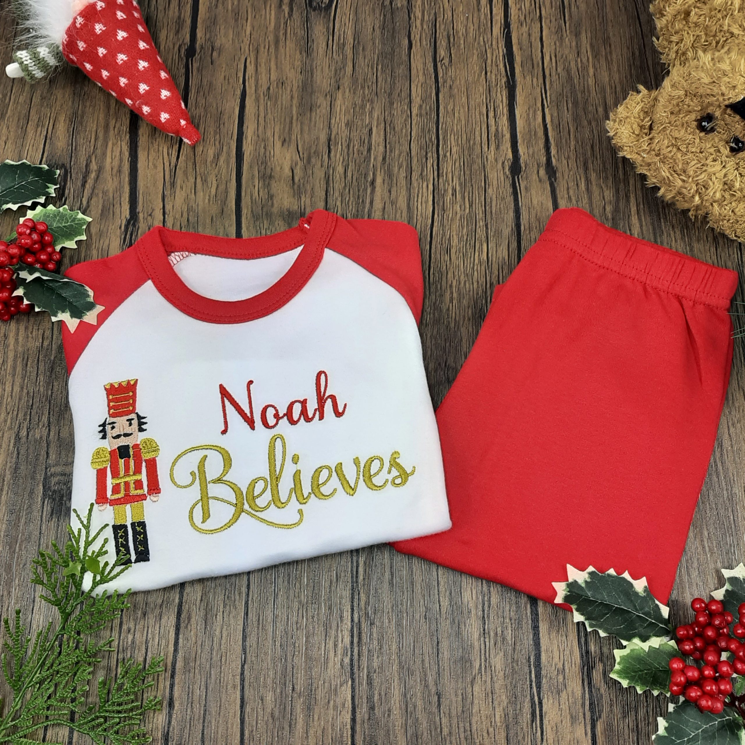 Nutcracker Christmas PJs in red and white for children with embroidered personalisation. Believes design. laid out