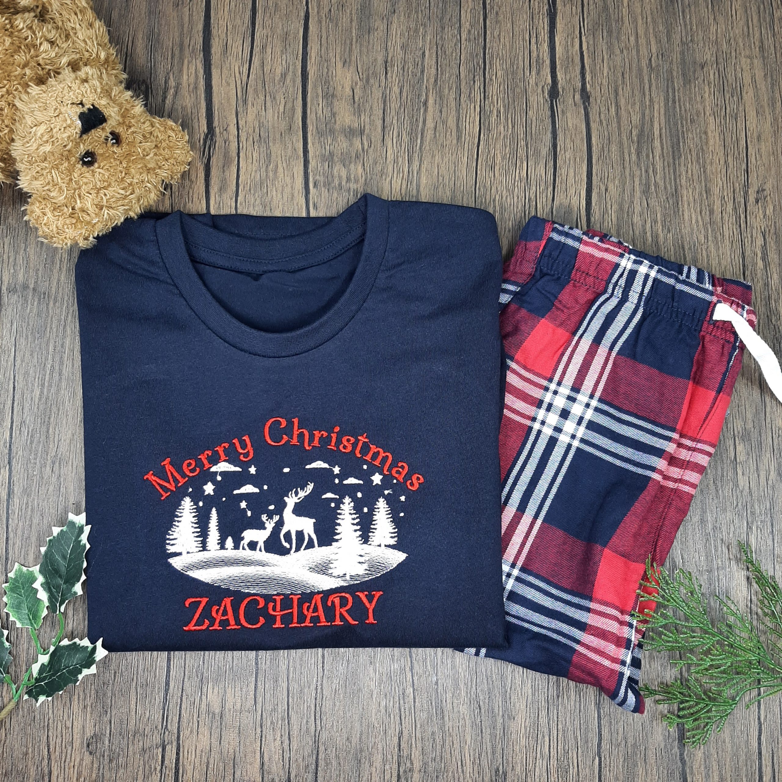 Family Tartan Winter PJs children's tarten winter pjs are great pyjamas for christmas. Featuring reindeer snow scene. All embroidered personalisation. Red name. Laid with teddy