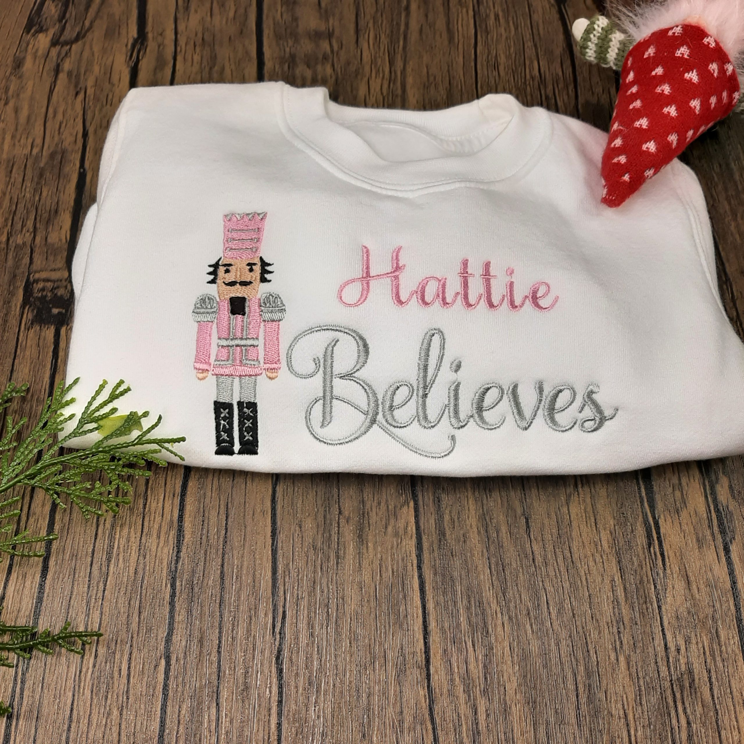 white Nutcracker Christmas Jumper in pink and silver, blue and silver or red and gold all personalised and professionally embroidered with name believes laid out