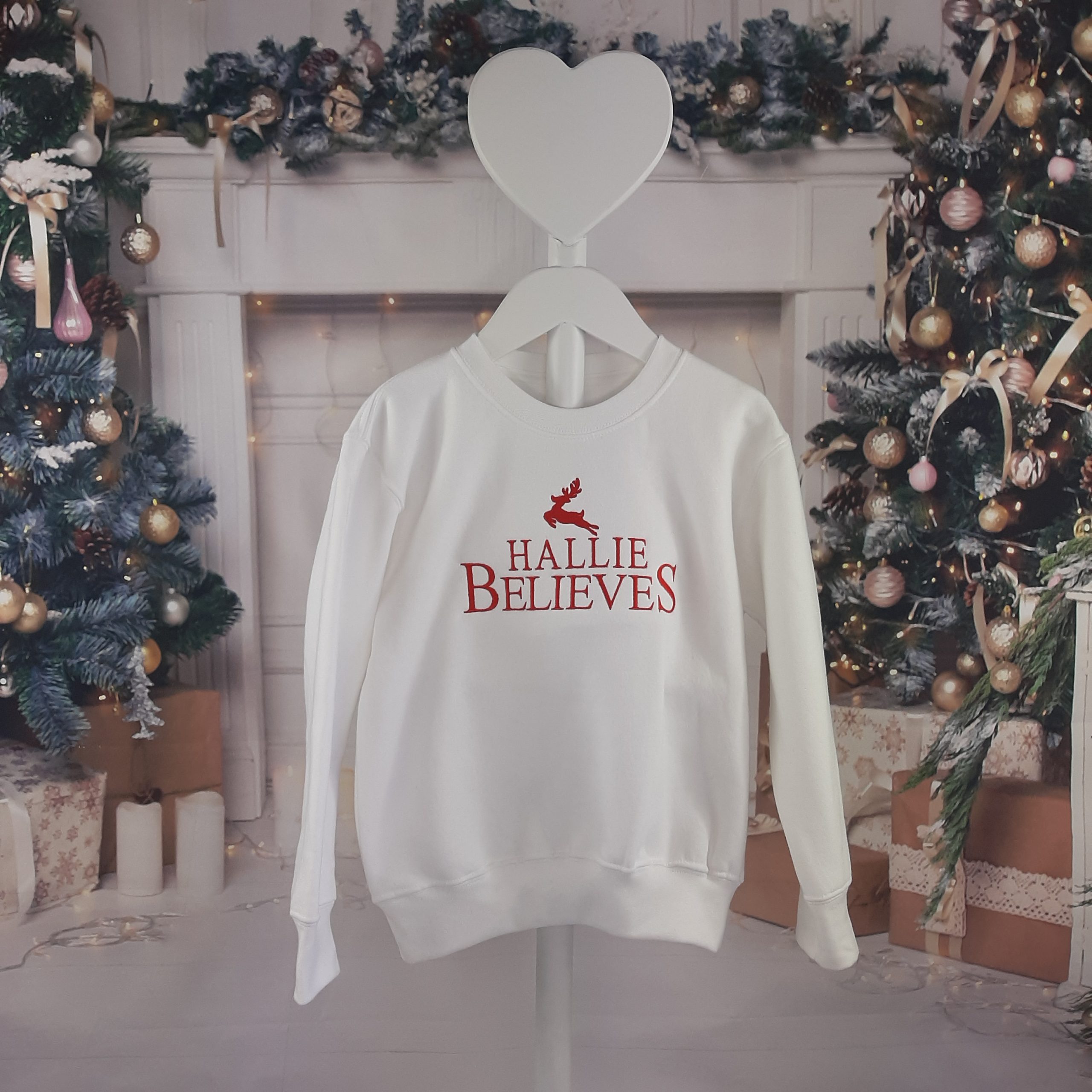 white Believes Christmas Jumper design featuring personalised name believes and cute reindeer all embroidered. Hung on model