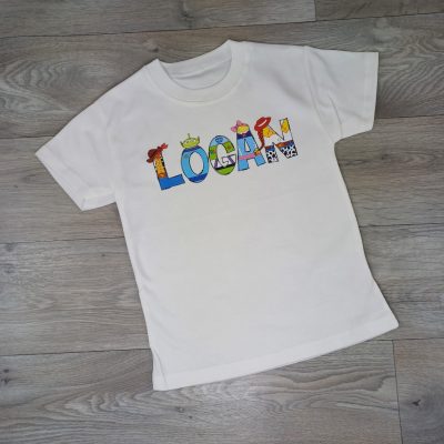 Personalised Toy Story Name T Shirt made from 100% cotton. Custom name design inspired by Buzz, Woody, Jessie, Forky, Bo Peep and Aliens. laid flat disney